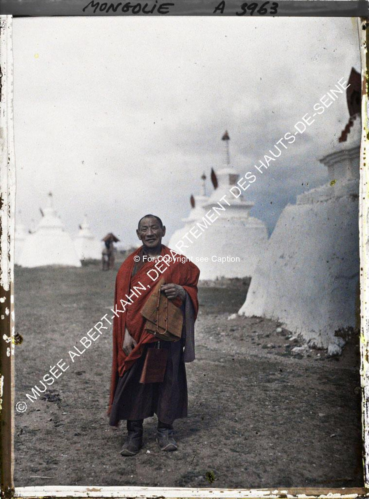 A monk standing among the stupas behind Gandan. Musée Albert-Kahn. A3963. Photo by Stéphane Passet, 